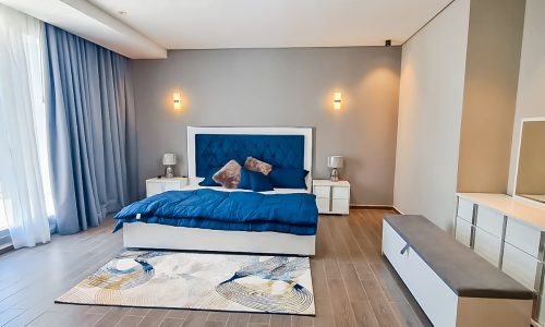 A luxurious bedroom with a blue bed and a white dresser.