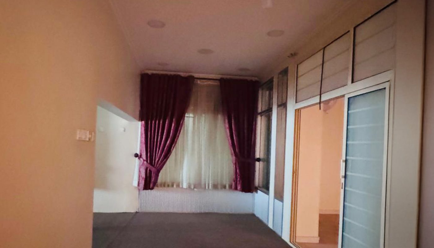 A narrow room with carpeted floor, ceiling fan, maroon curtains over a window, and glass sliding doors on one side.