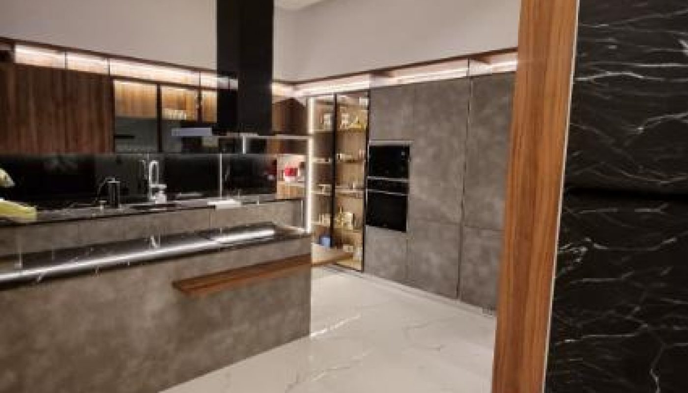 Modern kitchen with marble tile flooring, dark wood cabinetry, built-in appliances, and open shelving, illuminated by recessed and under-cabinet lighting.