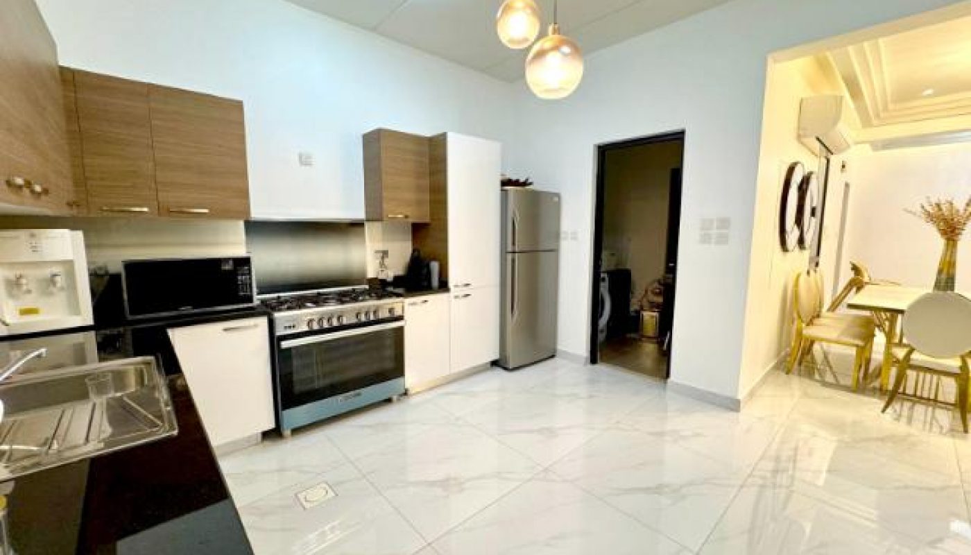 Modern kitchen with brown and white cabinets, stainless steel appliances, and pendant lights, adjacent to a dining area with a table and chairs.
