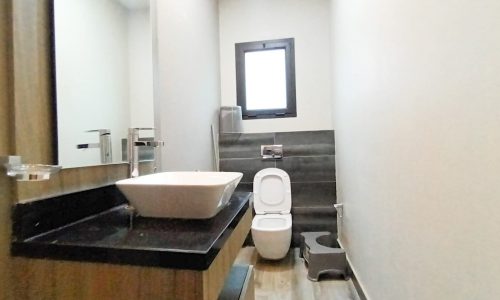 A cozy apartment in Adliya available for rent, featuring a small bathroom with a toilet and sink.