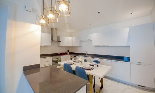 A luxurious white kitchen with a dining table and chairs.