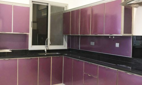 2BR Apartment for Sale in Saar on the 1st floor, with a purple kitchen and black counter tops.