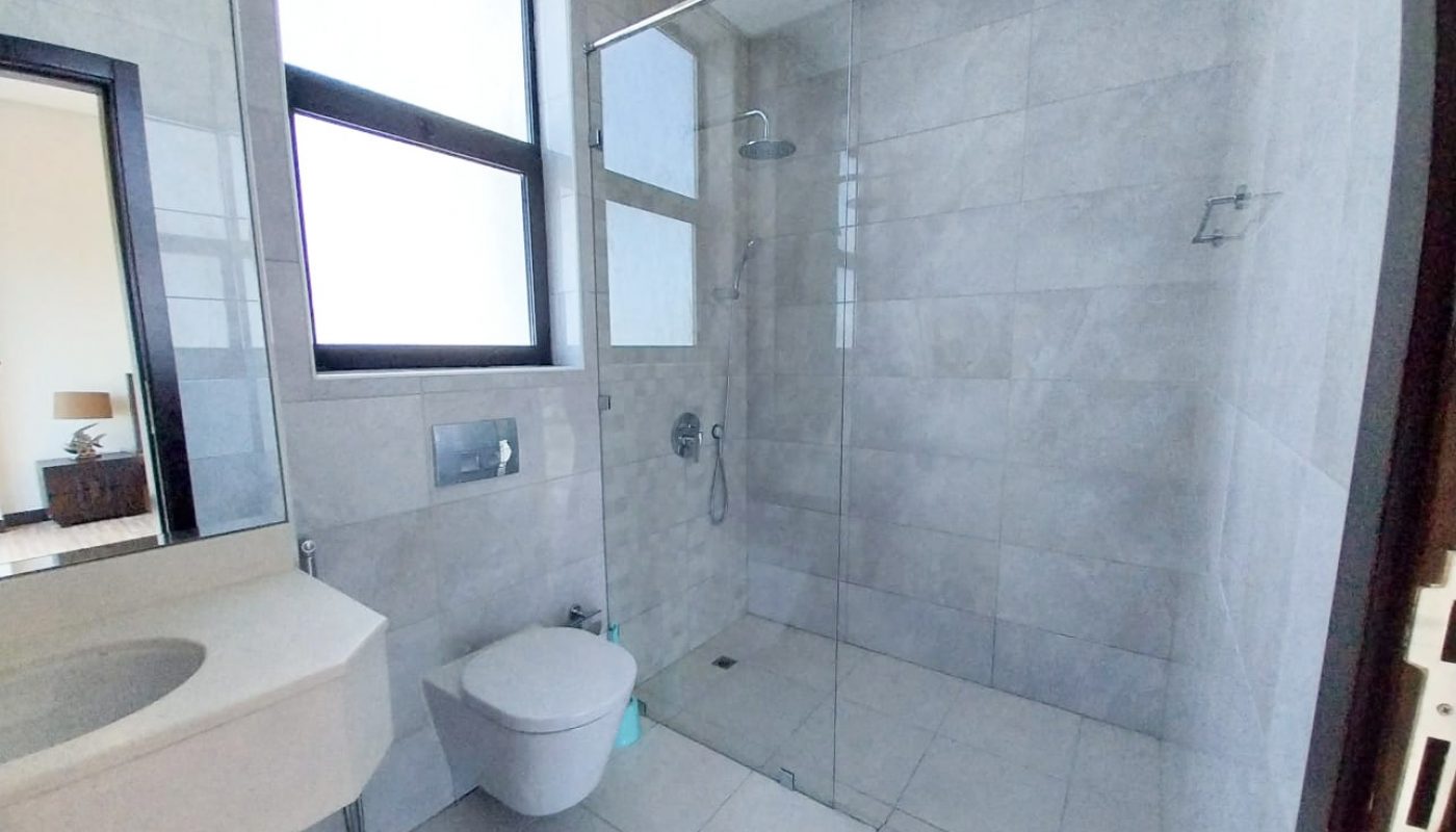 A luxurious bathroom with a glass shower and toilet in Amwaj featuring 2 bedrooms.