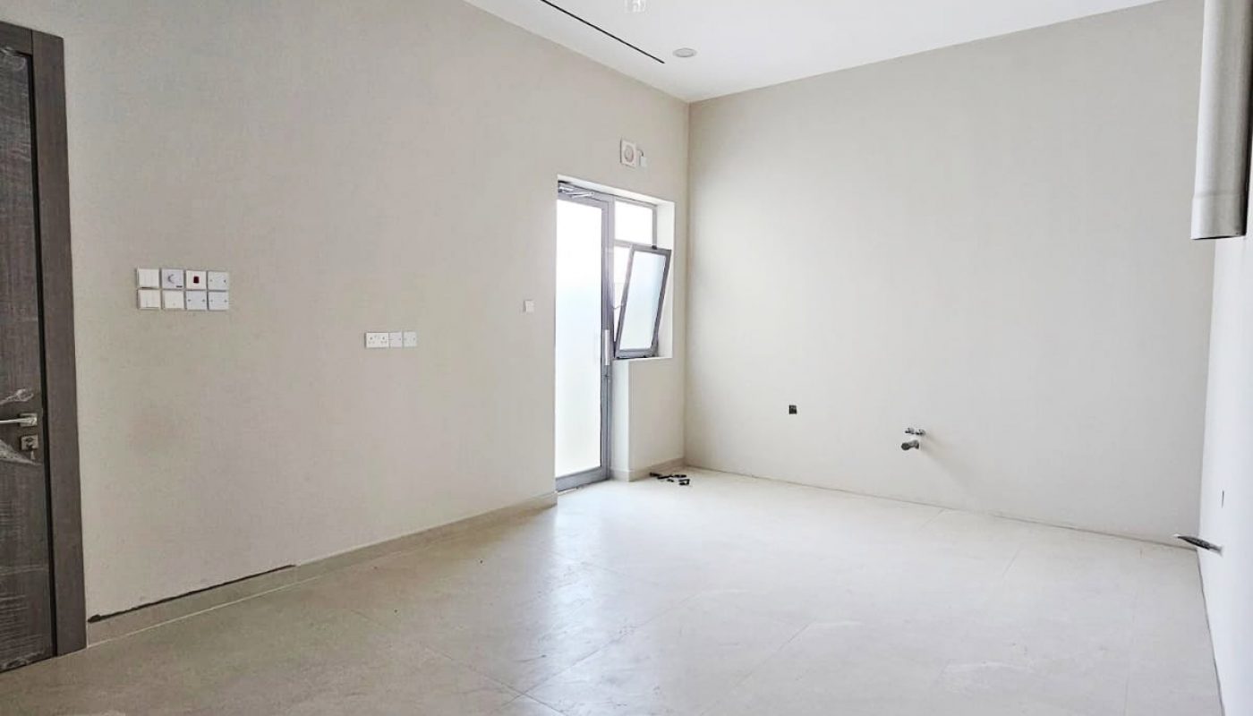 Empty room with light-colored walls and tiled floor, featuring a ceiling fan, door, and open window.