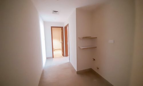 An empty hallway with shelves and a door in an Amazing SF 2BR Flat for Rent in Hidd.