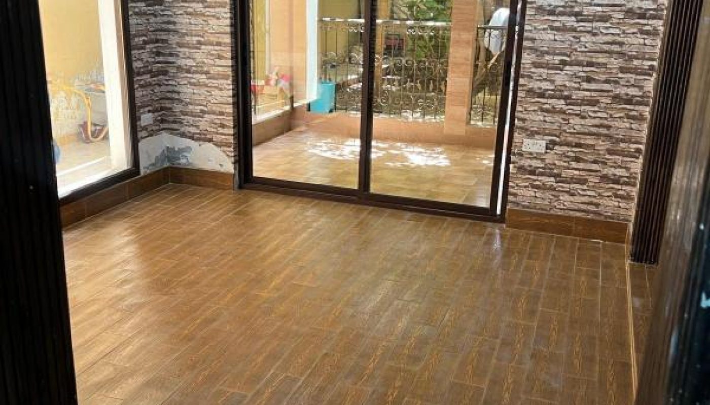 Empty room with wood-look tile flooring, stone-patterned wallpaper, ceiling fan, and large sliding glass doors opening to a patio.