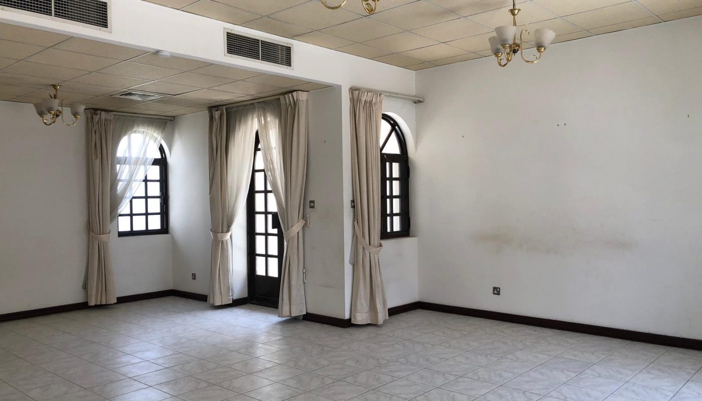 An empty room with tiled flooring, arched windows with curtains, ceiling lights, and a partial view of an air conditioning duct.