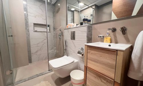 A luxurious and flat bathroom with a toilet, sink, and shower stall.