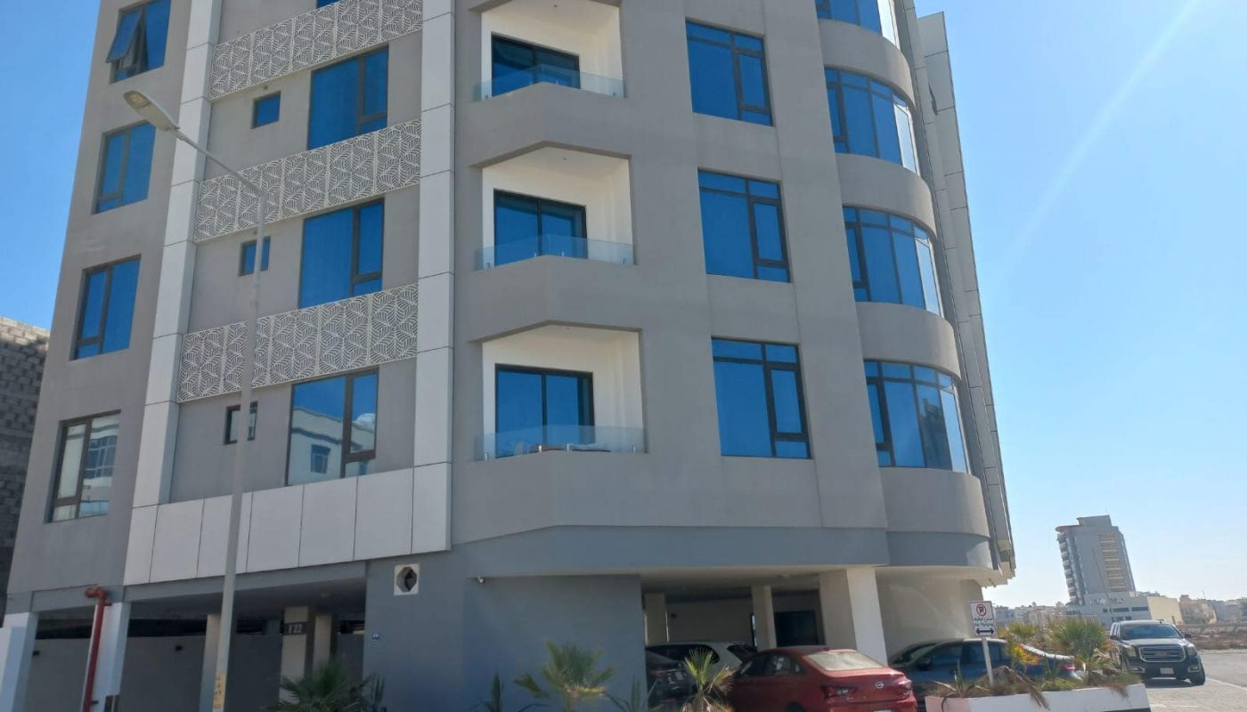 A Seef apartment building with cars parked in front of it, available for sale.