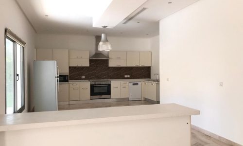 Modern kitchen interior with beige cabinetry, stainless steel appliances, and a marble countertop.