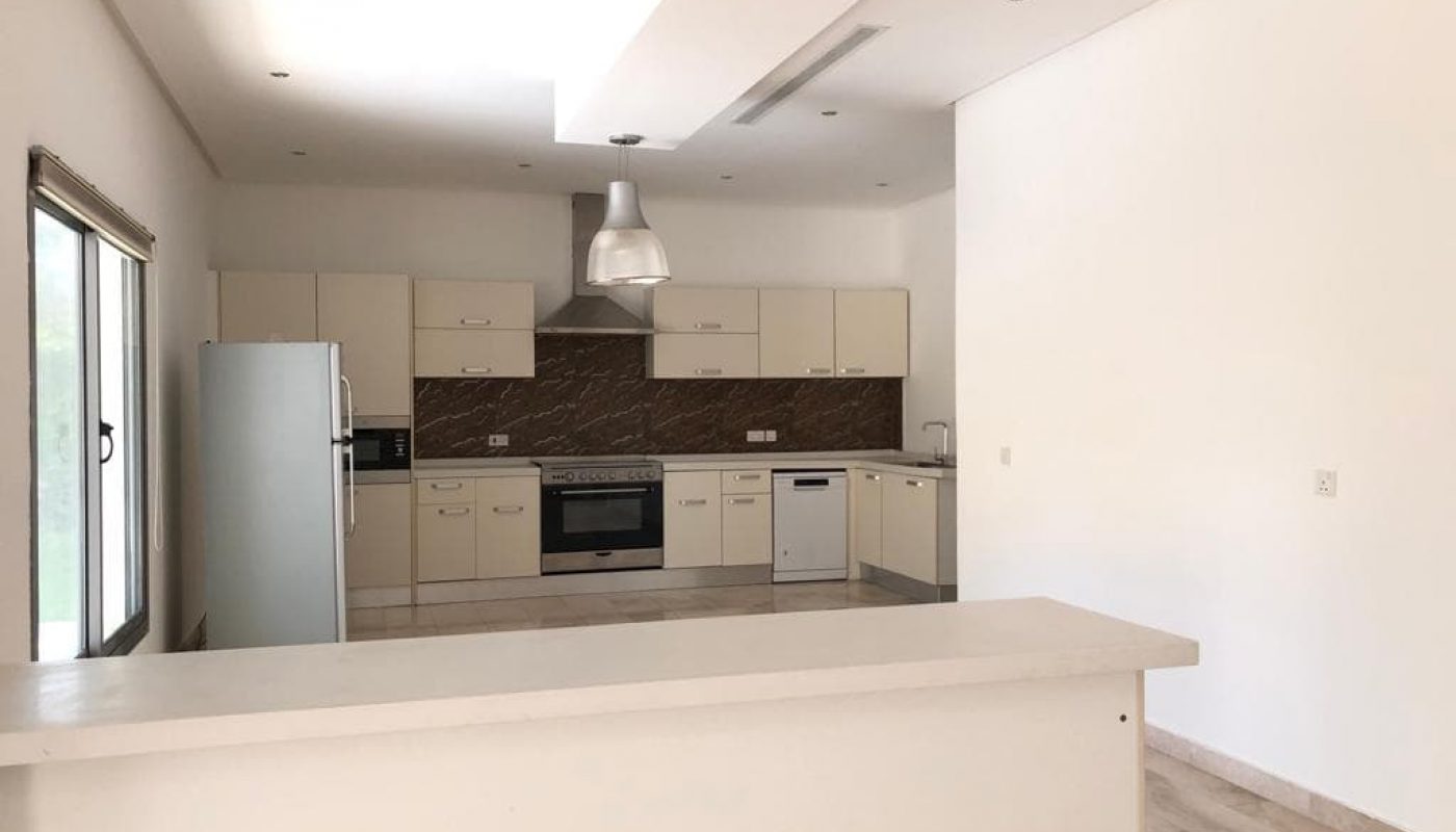 Modern kitchen interior with beige cabinetry, stainless steel appliances, and a marble countertop.
