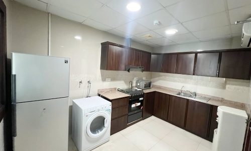 A kitchen with a washing machine, refrigerator, and semi furnished 2 bedrooms.