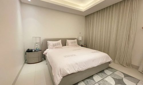 A modern bedroom with a neatly made bed, side tables, lamps, and a patterned rug, saved as an Auto Draft.