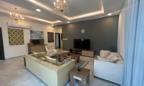 A modern living room with furniture and a chandelier in a 170 SQM, 3BR apartment for sale in Hidd.