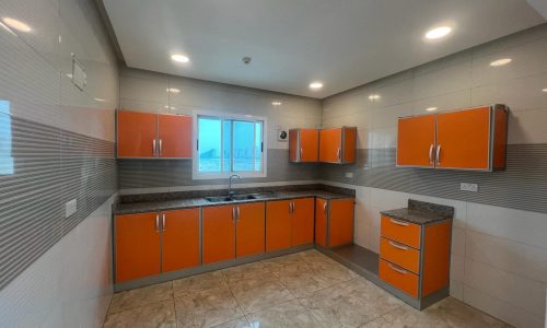 Apartment for Rent: Modern kitchen interior with orange cabinetry and stainless steel handles, featuring marble countertops and tiled flooring in the Galali area.