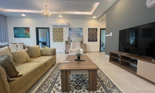 Modern living room with beige furniture and a TV in a 3BR apartment for sale in Hidd, measuring 170 SQM.