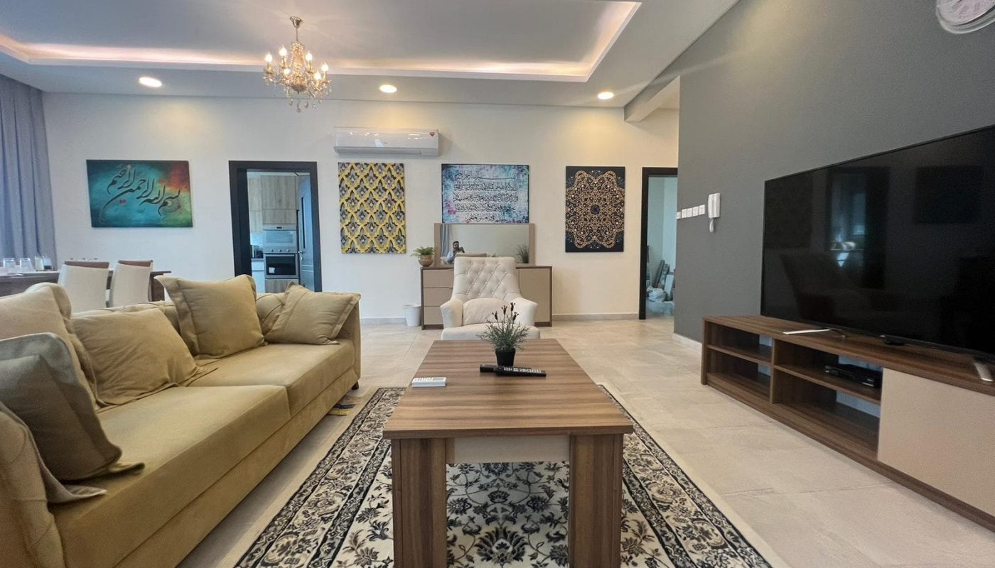 Modern living room with beige furniture and a TV in a 3BR apartment for sale in Hidd, measuring 170 SQM.