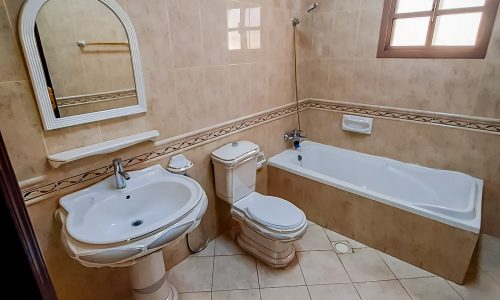 A 4 bedroom villa for rent in Janabiyah with a bathroom equipped with a toilet, sink, and tub.