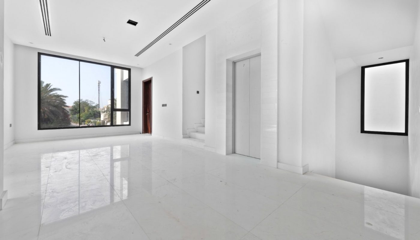 An empty white room with large windows.