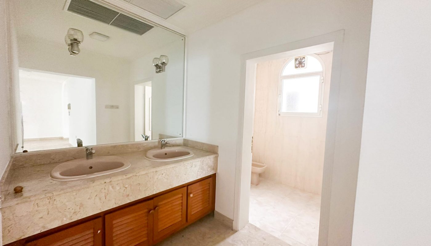 A spacious villa in Mahooz with three bedrooms, two sinks, and a mirror.