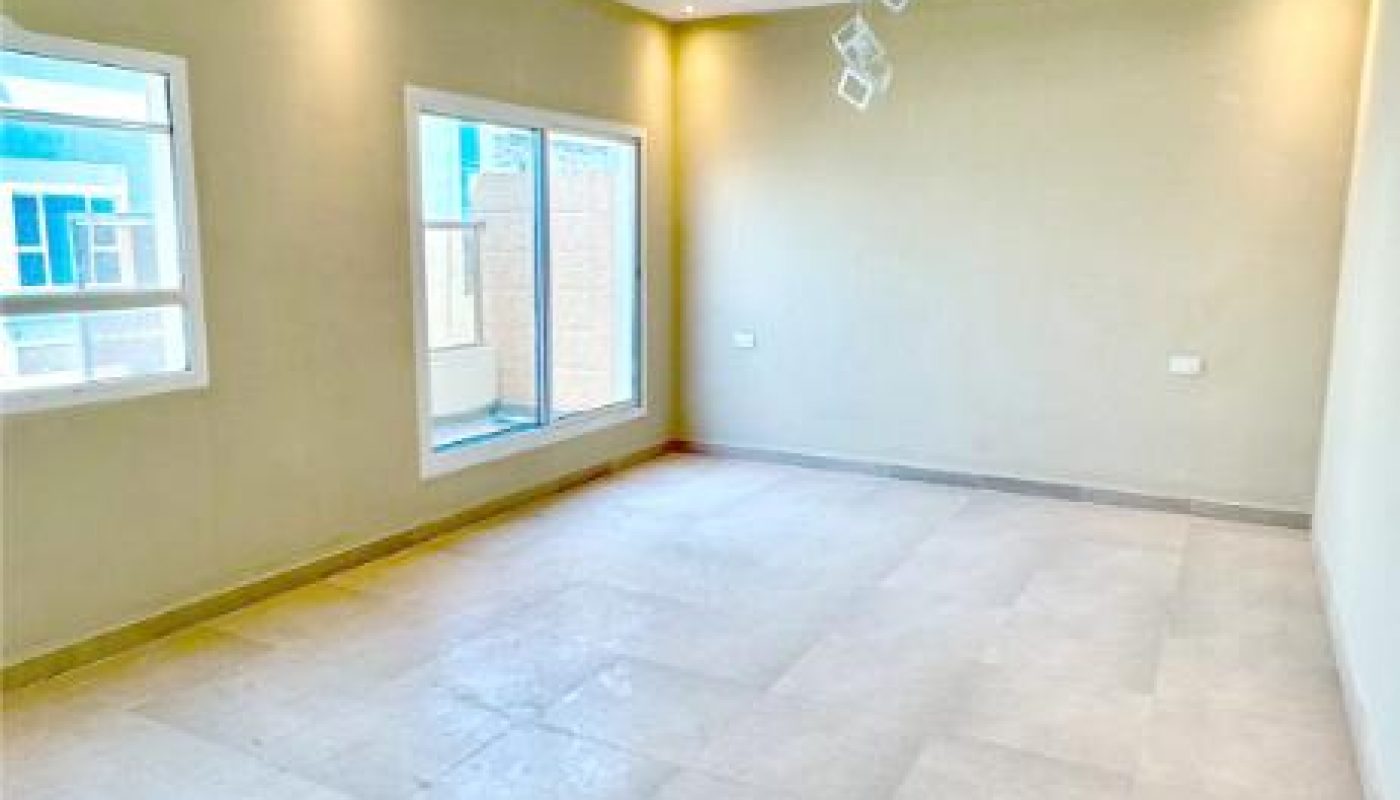 Empty room with light-colored tiled floor, beige walls, large windows, and a modern recessed ceiling with square light fixtures.