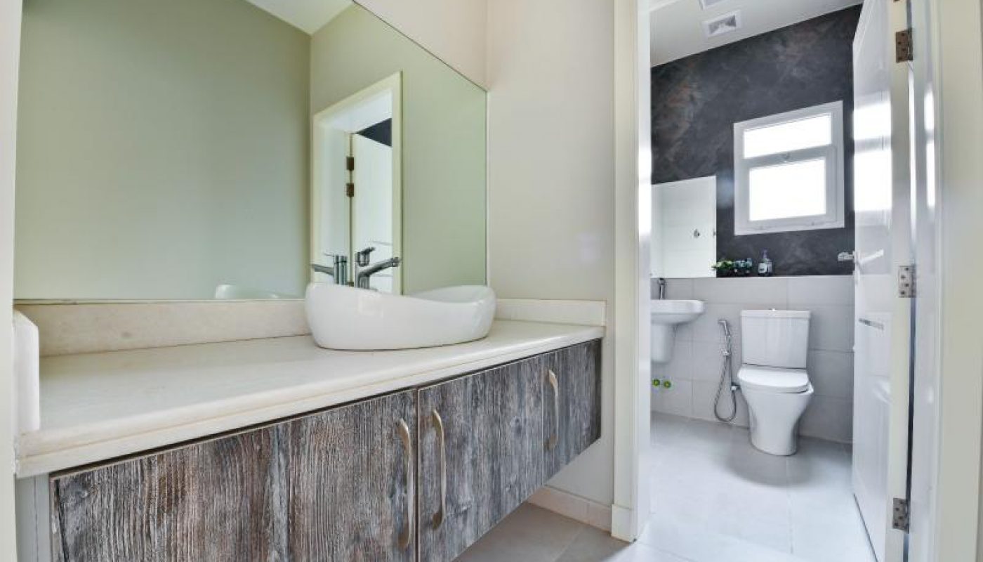 Modern bathroom with a wall-mounted vanity, vessel sink, large mirror, and a view into a toilet area with a window.