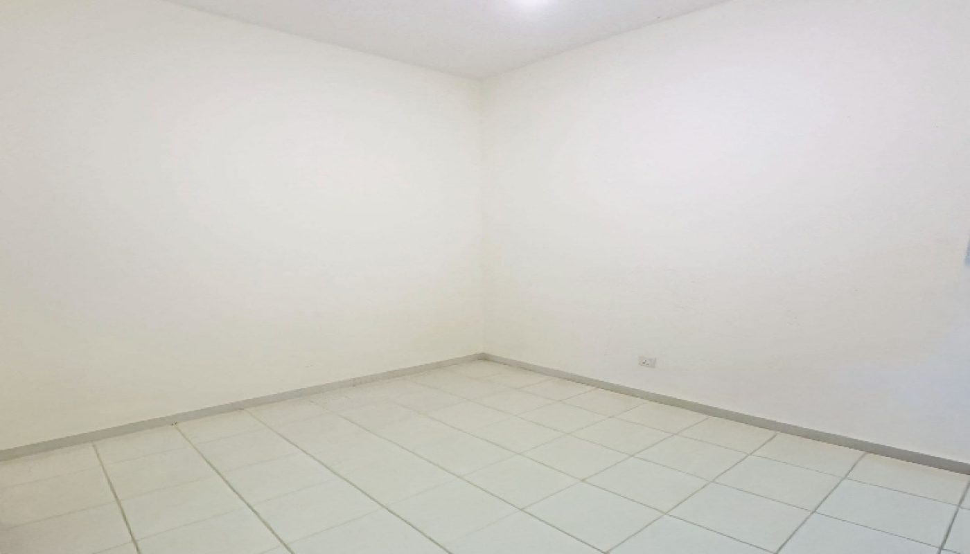 Empty room with white tiled floor, plain white walls, and a single exposed light bulb hanging from the ceiling.