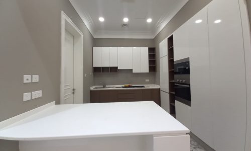 A brand new kitchen with white cabinets and a white countertop.