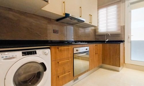 A brand new apartment for rent in Hidd with a kitchen equipped with a washer and dryer.