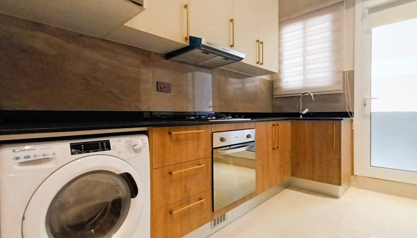 A brand new apartment for rent in Hidd with a kitchen equipped with a washer and dryer.