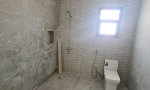 A stunning new villa for sale in Malkiyah with a bathroom featuring a toilet and a window.