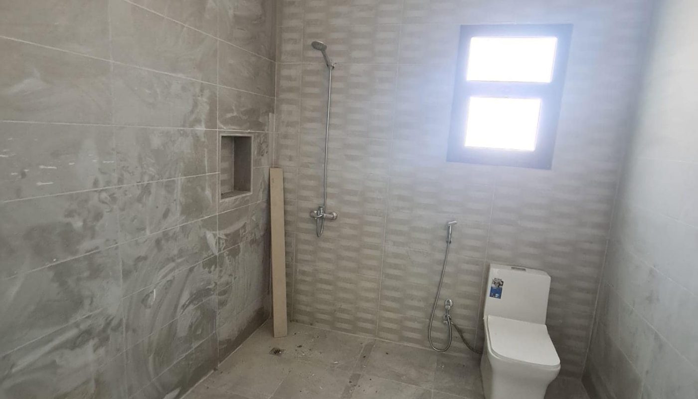 A stunning new villa for sale in Malkiyah with a bathroom featuring a toilet and a window.