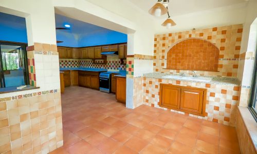 A kitchen with tiled floors and a sink in a huge luxury 4BR villa for sale in Sanad.