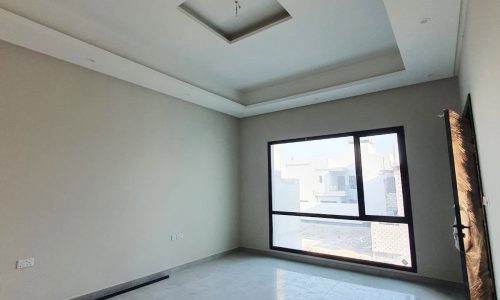 A bright, empty room with glossy tiled flooring, a large window, and a modern recessed ceiling. The room features a neutral color scheme and benefits from natural lighting coming through the window—like an ideal auto draft waiting for your creative touch.