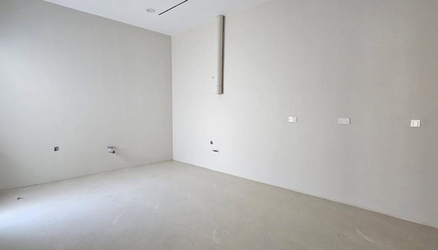 Empty room with beige walls and floor, ceiling fan, recessed lights, and electrical outlets.