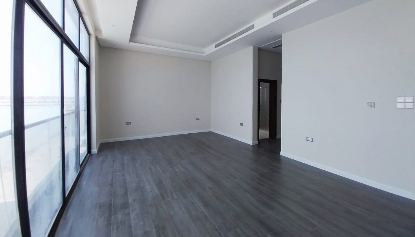 Unfurnished modern room with floor-to-ceiling windows, light-colored walls, and dark wood flooring.