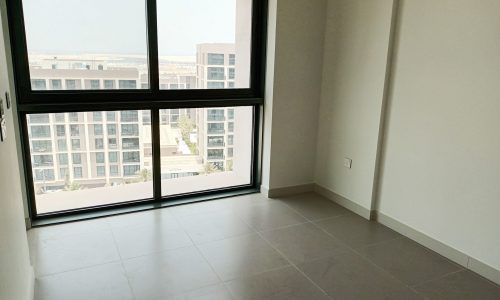 An empty luxury apartment with a stunning view of the city from a large window overlooking Diyar Al Muharraq.