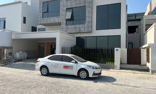 A white luxury car is parked in front of a modern house.