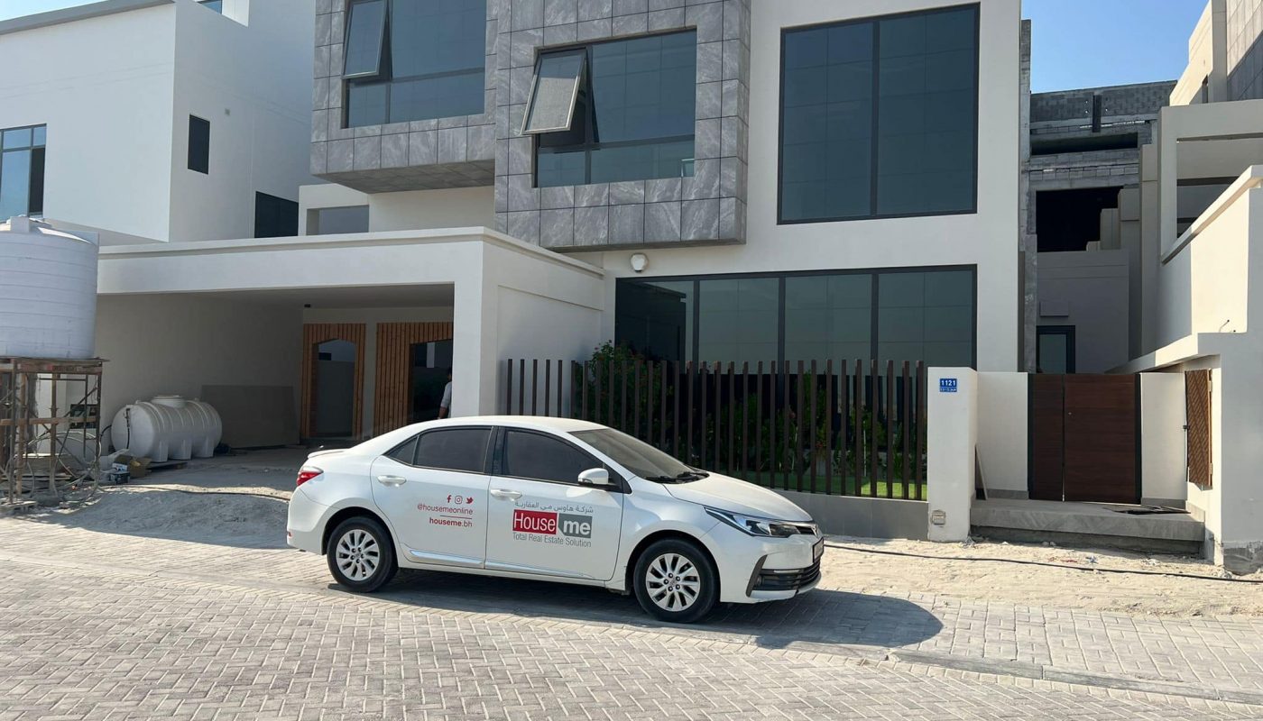 A white luxury car is parked in front of a modern house.