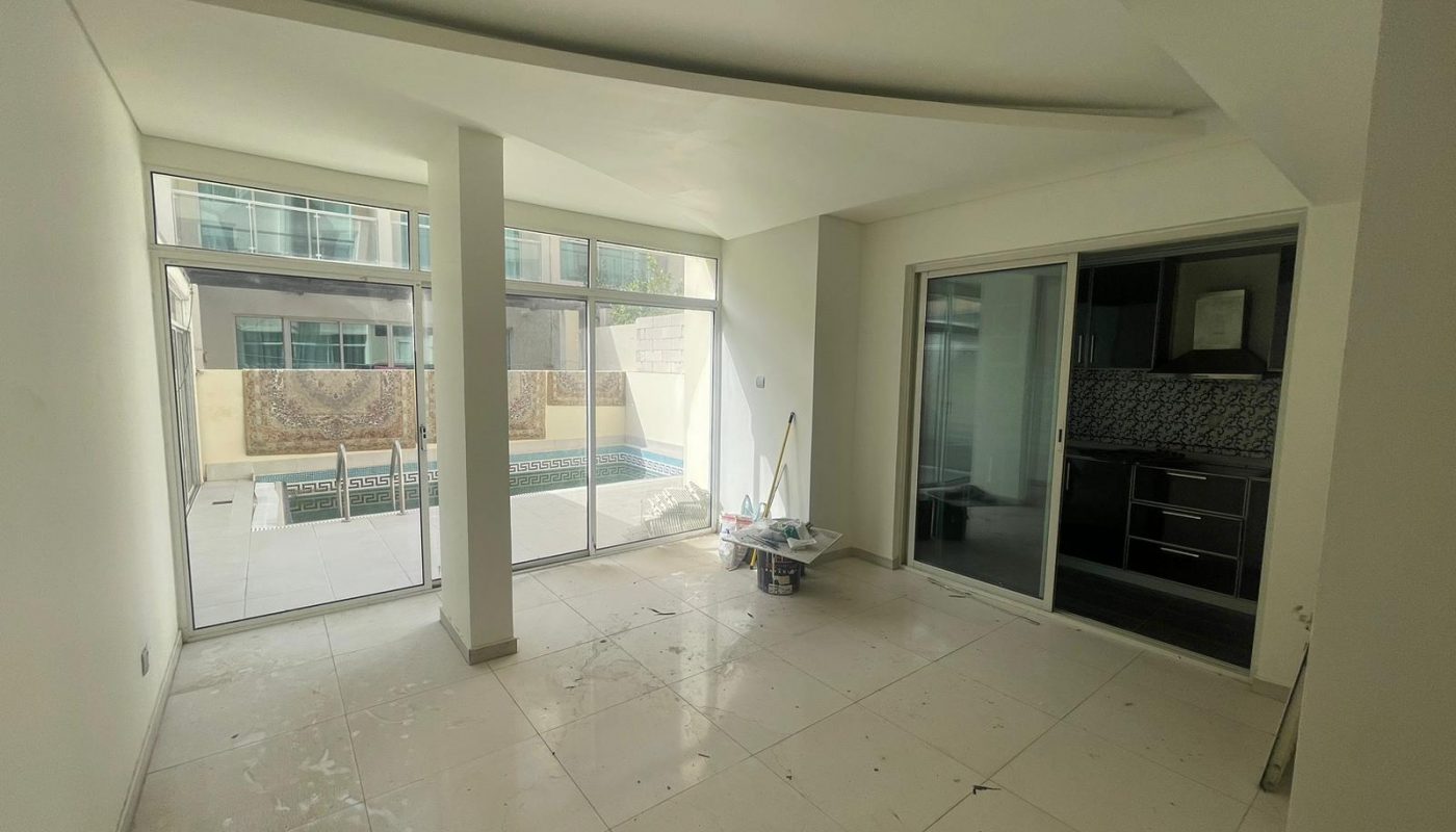 Unfurnished room with tiled floors, large glass doors leading to a pool area, and cleaning supplies placed near the center.