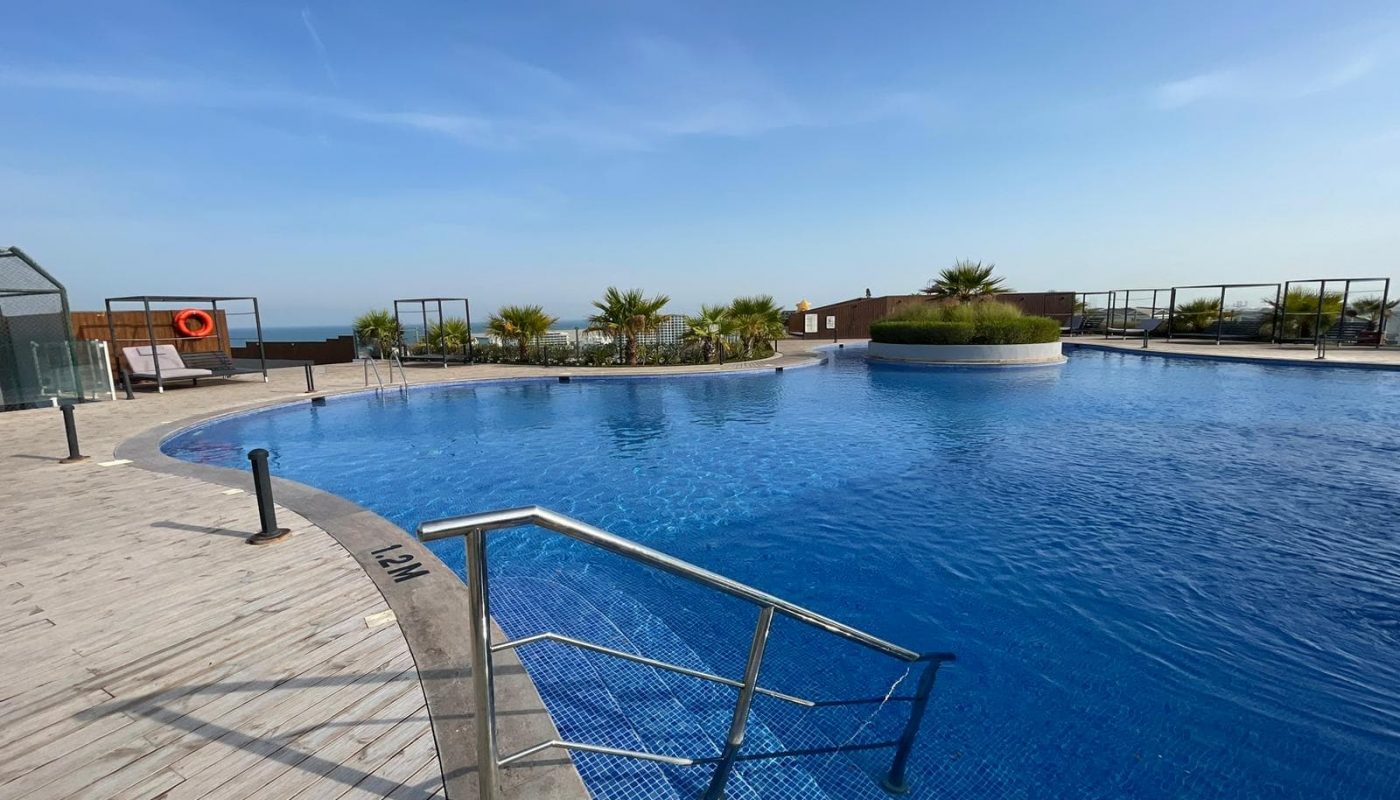 Elegant swimming pool with a wooden deck and a view of the ocean on Dilmunia Island.