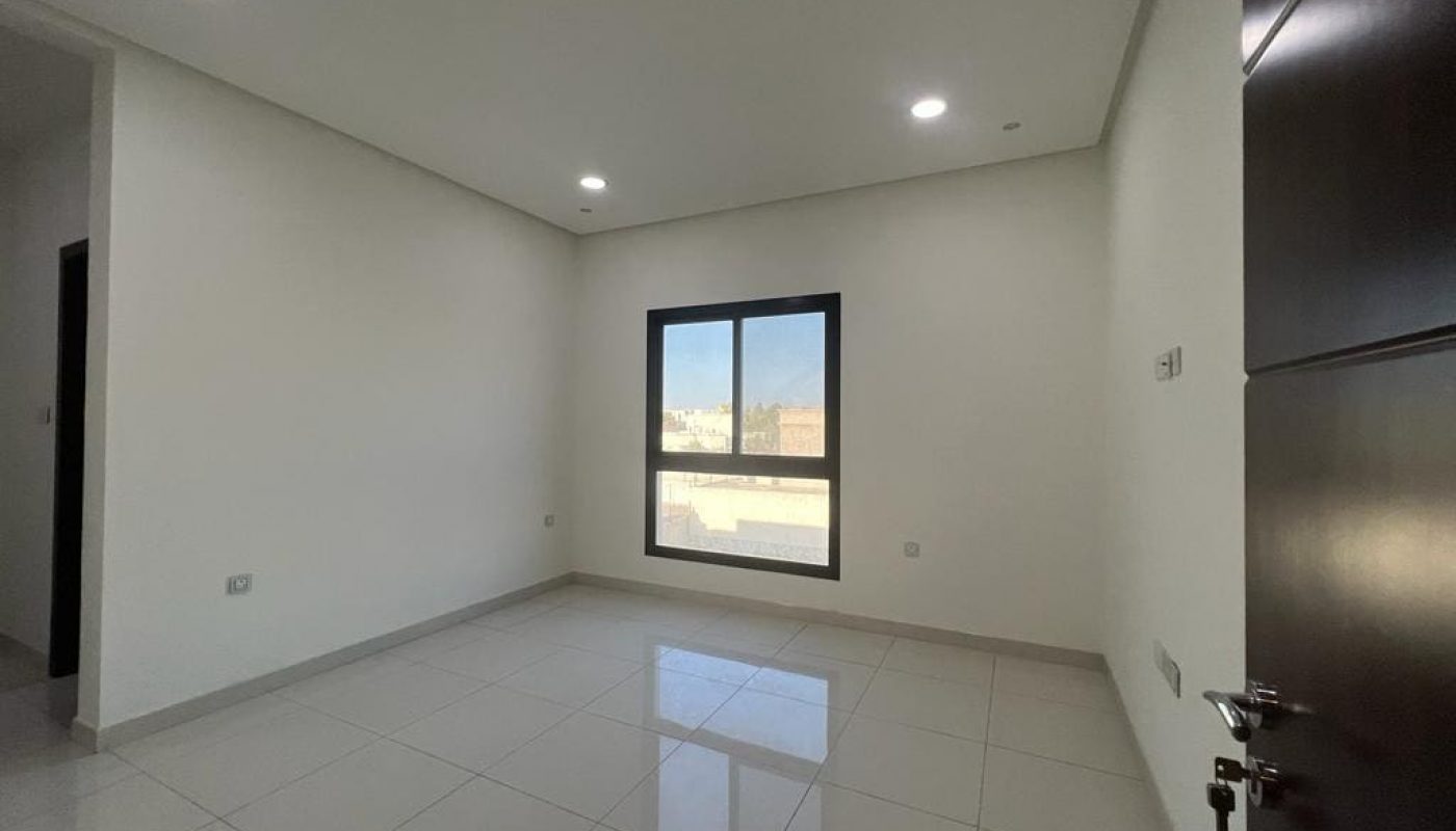A luxurious apartment with three bedrooms, featuring an empty room adorned with tile floors and a window.