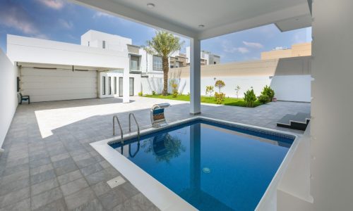 A fancy home with a pool in the backyard and a bright garden.