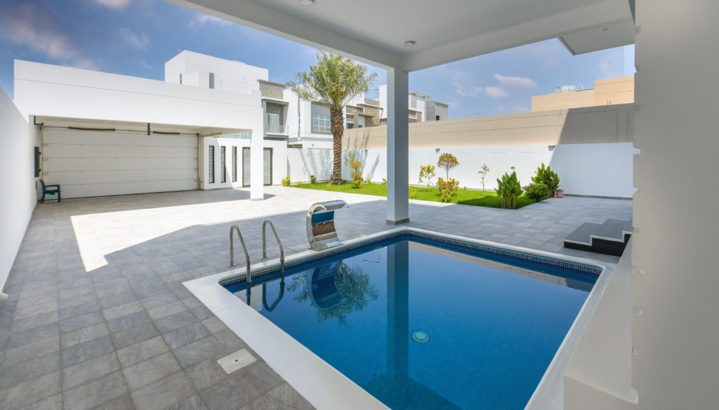 A fancy home with a pool in the backyard and a bright garden.