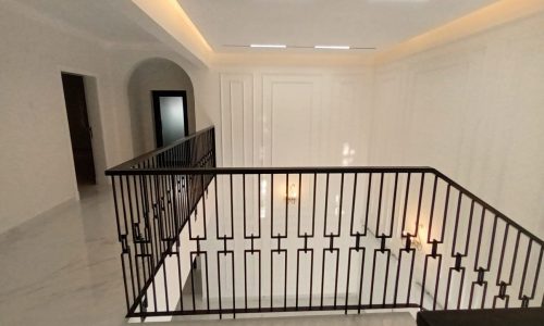 A luxurious white staircase with a metal railing in a spacious house.