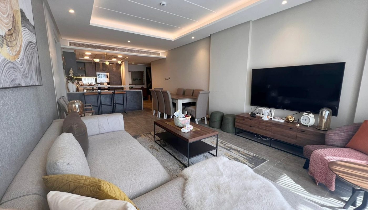 A luxurious flat in Hidden Heights for sale, featuring a living room with stylish couches and a TV.