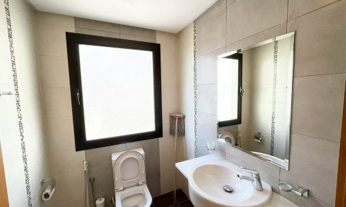 A stunning apartment with a bathroom featuring a sink, toilet, and window.