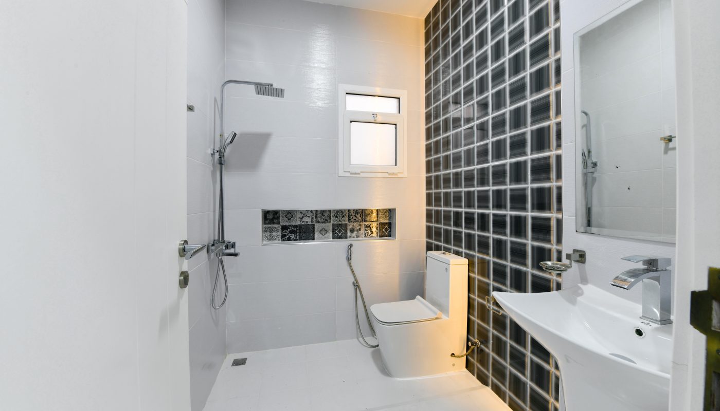 A luxurious apartment for sale, featuring a bathroom with black and white tiled walls and a toilet.