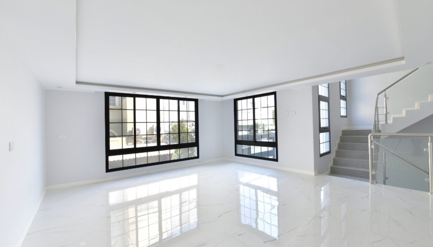 Bright, empty room with large windows, glossy white marble floor, and a staircase with a glass railing leading to an upper level.